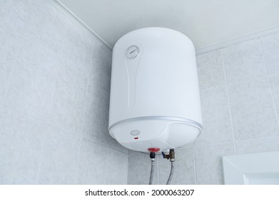 White electric water heater boiler on the wall in the bathroom.