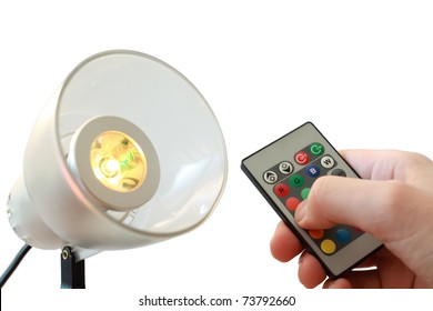 White electrical lamp, near it remote controller in man hand