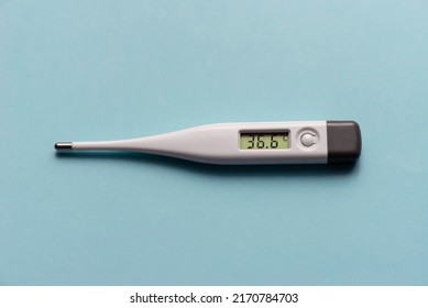 White Electronic Thermometer Shows Normal Body Temperature On A Blue Background