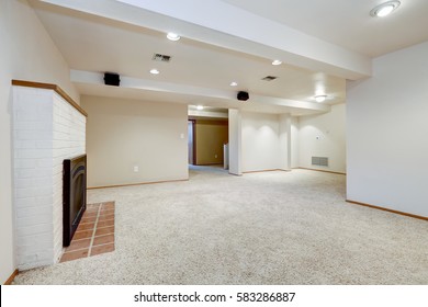 White Empty Basement Room With Fireplace And Wall To Wall Carpet Floor. Northwest, USA