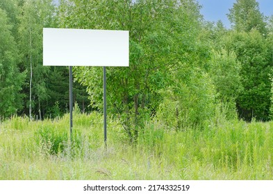 A White Empty Billboard In The Forest Among The Trees. Posting Information In A Public Park Or Drawing Attention To Environmental Issues. Summer, Copy Space.