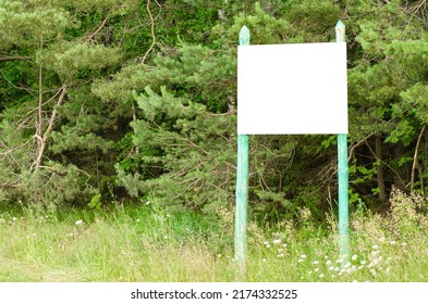 A White Empty Billboard In The Forest Among The Trees. Posting Information In A Public Park Or Drawing Attention To Environmental Issues. Summer, Copy Space.