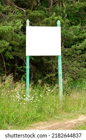 A White Empty Billboard In The Forest Among The Trees. Posting Information In A Public Park Or Drawing Attention To Environmental Issues. Summer, Copy Space.