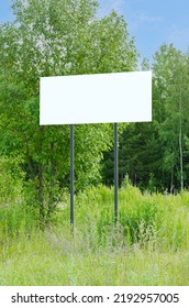 A White Empty Billboard In The Forest Among The Trees. Posting Information In A Public Park Or Drawing Attention To Environmental Issues. Summer, Copy Space.