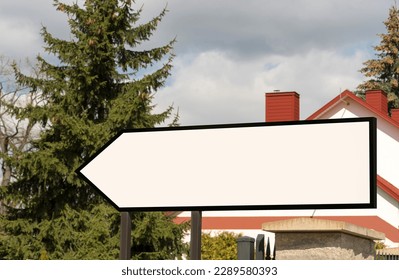 White, empty board - directional arrow. Against the background of a spruce and a house. A place for any inscription (for example, an advertisement). Direction and indication .  