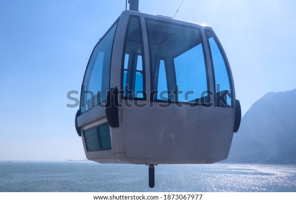 A white empty cable car is floating in\
the sky in afternoon with lake and mountain\
view