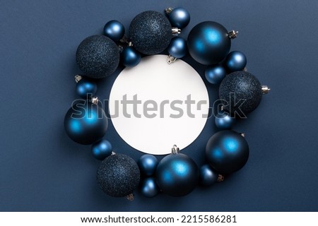 White empty circle with frame of blue matte and glitter Christmas balls on dark blue background with copy space