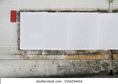 White Empty Creased Street Posters Glued To Grungy Urban Stained Brick Wall