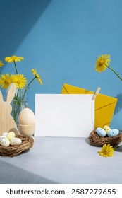 White empty envelope Postcard copy space traditional greeting card to christian holiday. Festive mood composition with bunnies eggs and yellow flowers on pastel blue background. Sustainable natural