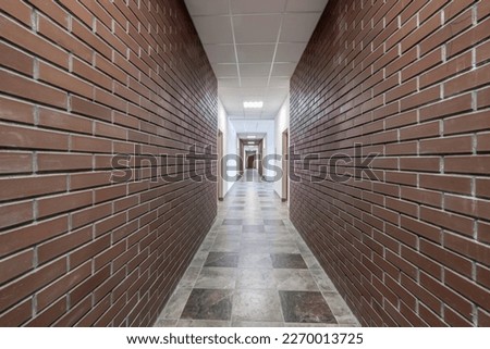white empty long corridor with red brick walls in interior of modern apartments, office or clinic.