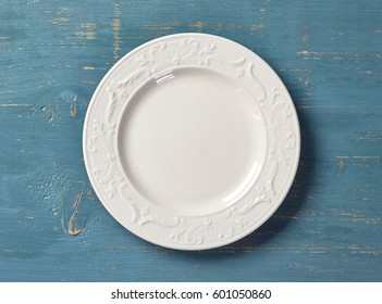 white empty plate on blue wooden table, top view