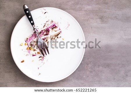White empty plate with piece of cake leftovers from above on gray background. Copyspace for text 