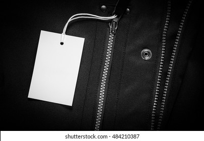 White Empty Tag On A Dark Jacket With Zippers. Paper Cloth Label Mockup.