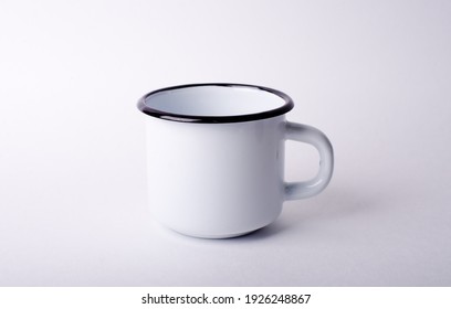 White Enamel Metal Mug On A Light Surface.