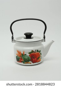 White enamelled teapot with vegetable pattern isolated on white background