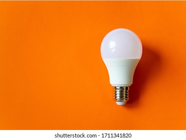 White energy saving light bulb isolated on an orange background with copy space. Concept of eco-friendly life. Minimal thing. LED white bulb, concept of new idea. Minimal think.