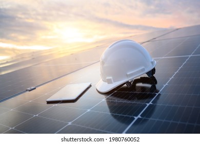White engineer hard hat and a tablet placed on the solar panel At a photovoltaic power station working on solar energy storage in the industry.