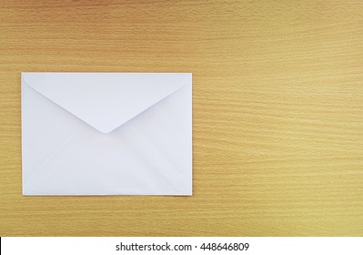 A White Envelope On The Wood Desk, Top View At The Studio.