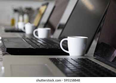 White Espresso Coffee Cups Next To Many Laptops