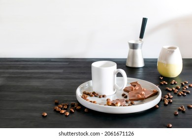 white espresso cup, mug, chocolate, coffee beans on plate kitchen table, utensils dishware, coffee pot on black wooden shelf. Early morning french home hot beverage breakfast, copy space.