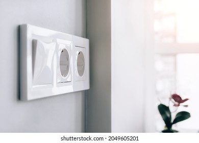 White european electrical socket outlets and switch on gray wall in light modern kitchen by the window. Selective focus - Shutterstock ID 2049605201