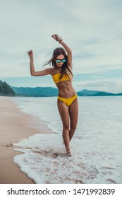 white European tourist girl relaxing at the exotic Thailand Phuket beach near asian rainforest, wearing yellow bikini