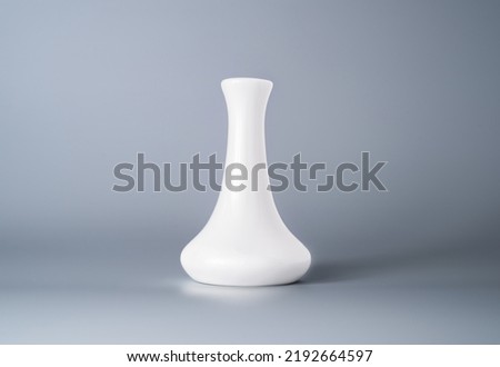 White expanded ceramic or glass vase. Empty waterglass isolated on gray background in studio. Flower vase. Home decor, interior decoration. Modern glassware. Handmade vessel.