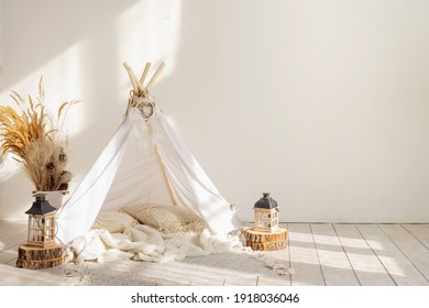 White fabric kids teepee and Native American decor in the interior of the children's room with copy space.