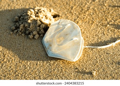 White Face Mask N95 discarded on the sand at a beach in Brazil. Coronavirus COVID-19 pandemic pollution, impact on nature. Ocean plastic Pollution. Microplastics in the water. - Powered by Shutterstock