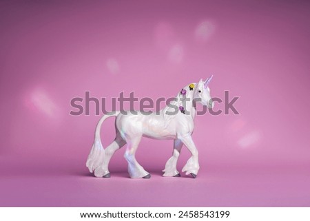 white fairy unicorn toy on a pink background with a rainbow glow