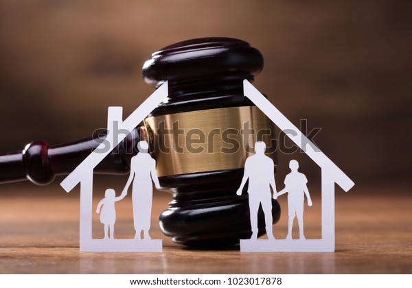 White Family Paper Cut Out In Front Of Judge Gavel\
On The Wooden Desk