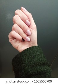 White Female Hand With Elegant Pale Pink Gel Polish And Rhinestones, Green Wool Coat Sleeve 