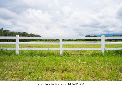 White Fence In Farm Field And Overcast Sky