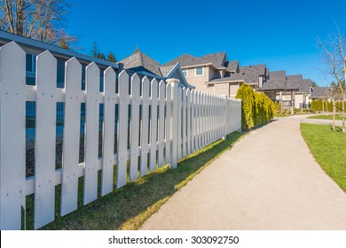 white fence with green lawn and houses.