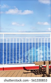 White fence of a ship with blue sky, sea water is colorful, floor is made with woods, sunlight around the area.