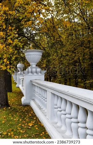 White fence with vases in the autumn park.
