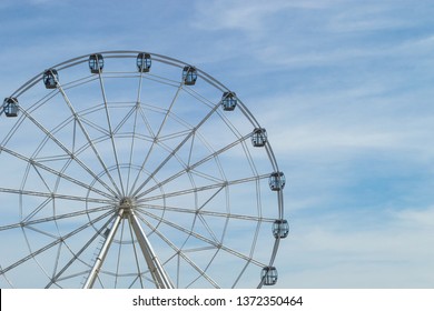 White Ferris Wheel With Glass Light-blue Cabins Against The Blue Sky. Wheel In Amusement Park. Front View, Copy Space.