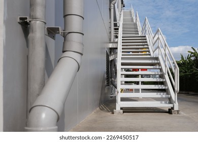 white fire exit stair of the large building against the blue sky. outdoor metal stair step. fire escape stairway.