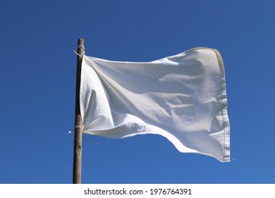 The White Flag Against The Blue Sky.  Surrender Concept.