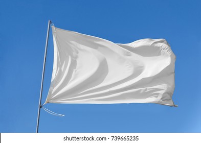 White flag attached to a flagpole waving on the sky - Shutterstock ID 739665235