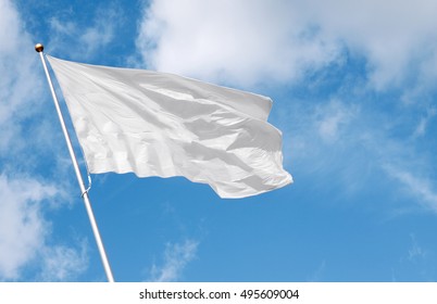 White Flag Waving In The Wind Against Cloudy Sky. Perfect Mockup To Add Any Logo, Symbol Or Sign