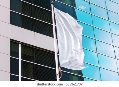 White flag waving in the wind with office building in the background. Perfect mockup to add any logo, symbol or sign