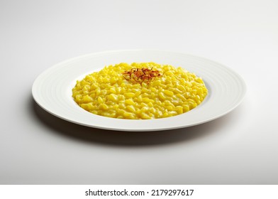 White flat plate with yellow risotto and saffron pistils isolated on white background