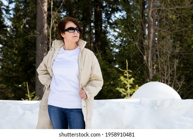 White Fleece Crewneck Sweatshirt Mockup Featuring A Woman Wearing Beige Quilted Coat In The Snowy Woods. Heavyweight Sweatshirt Template 