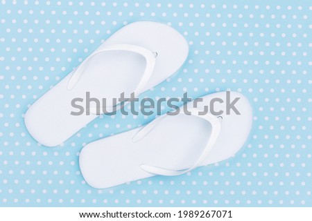 White flip flops shoes, top view, on blue polka dots Pattern. Toe sandals , flat lay, text place. Summer background with flipflops shoes