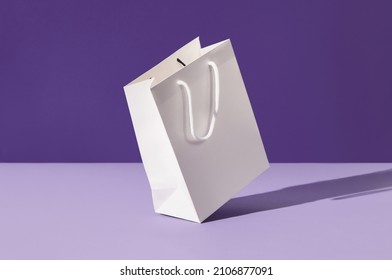 White floating paper shopping bag on purple background. Shopping sale delivery concept