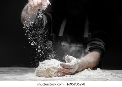 White flour flies in air on black background, pastry chef claps hands and prepares yeast dough for pizza pasta. - Powered by Shutterstock