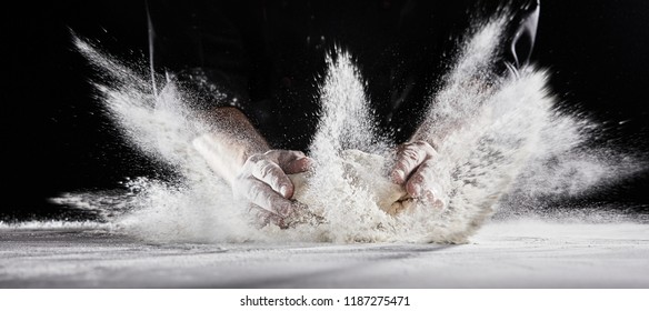 White Flour Flying Into Air As Pastry Chef In Black Suit Slams Ball Dough On White Powder Covered Table