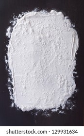 white flour sprinkled on a dark wooden table. top view