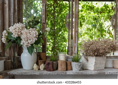 white flowers in clay pots arranged on the edge of wooden window box with open shutters - Powered by Shutterstock